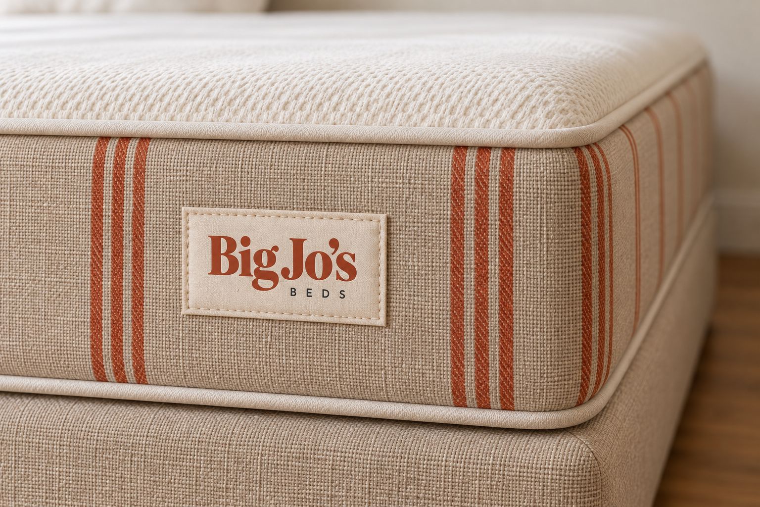Close-up of the Flax finish: woven fabric, clay ticking stripes, cream piping and the sewn-on Big Jo’s Beds label.